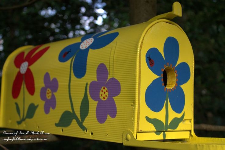 a yellow mailbox with flowers painted on it