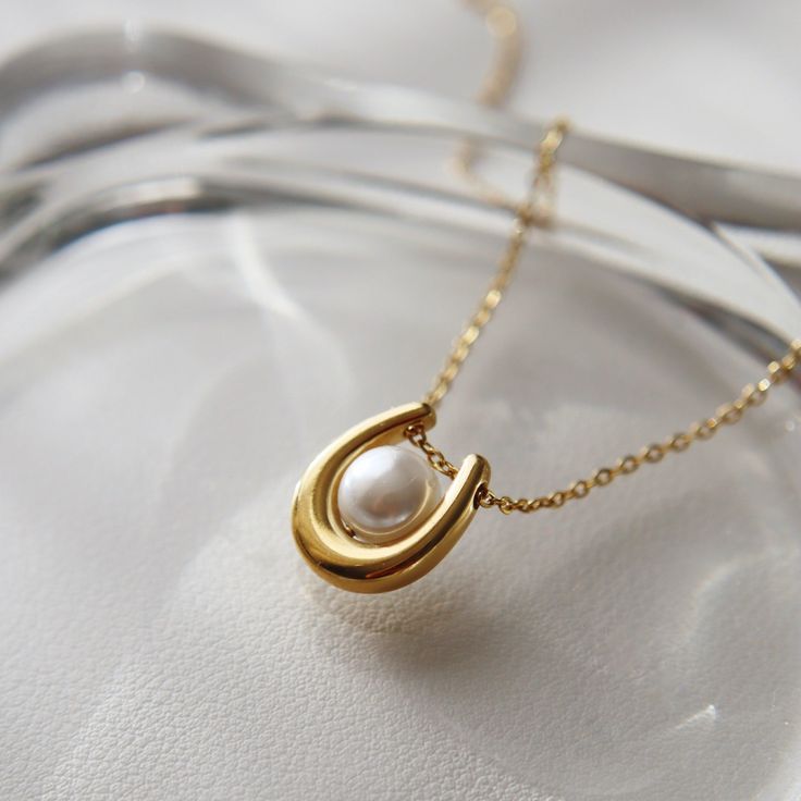 Featuring a stunning U-shaped pendant adorned with a lustrous pearl, the Ava Necklace adds a touch of elegance to any outfit. Treat yourself or a loved one to a beautiful and timeless accessory that will surely make a statement. -stainless steel, gold plated-15" with 2" extender Elegant Pearl Jewelry With Initial Pendant, Elegant Necklace With Pearl Charm As Gift For Her, Elegant Pearl Initial Pendant Jewelry, Pearl Necklace With Initial Pendant As Gift, Elegant Pearl Necklace With Initial Pendant And Pearl Charm, Elegant White Pearl Necklace With Initial Pendant, Elegant Pearl Charm Necklace With Oval Pendant, Timeless Pearl Necklace With Clavicle Chain As Gift, Timeless Pearl Necklace With Clavicle Chain