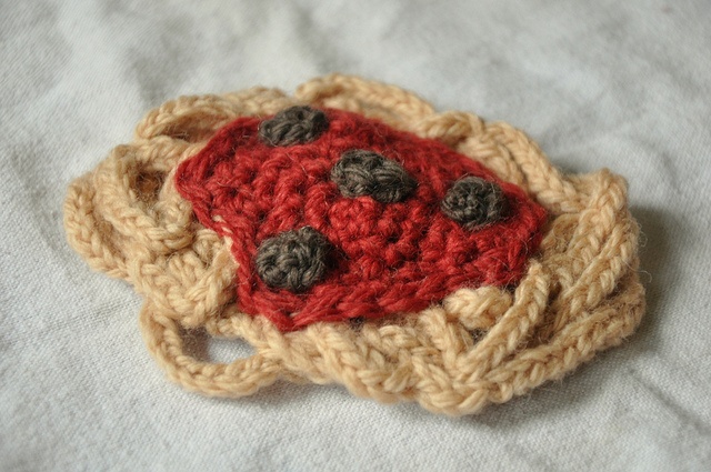 a crocheted brooch with buttons is laying on a white cloth covered surface