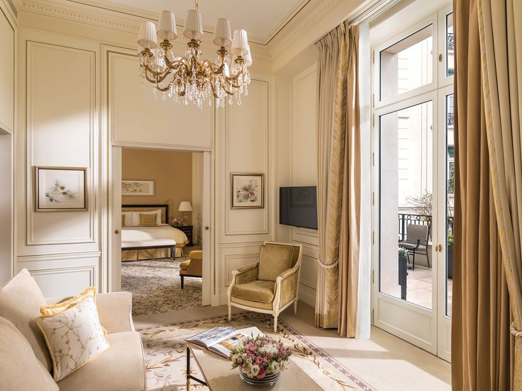 a living room filled with furniture and a chandelier hanging from the ceiling over a doorway