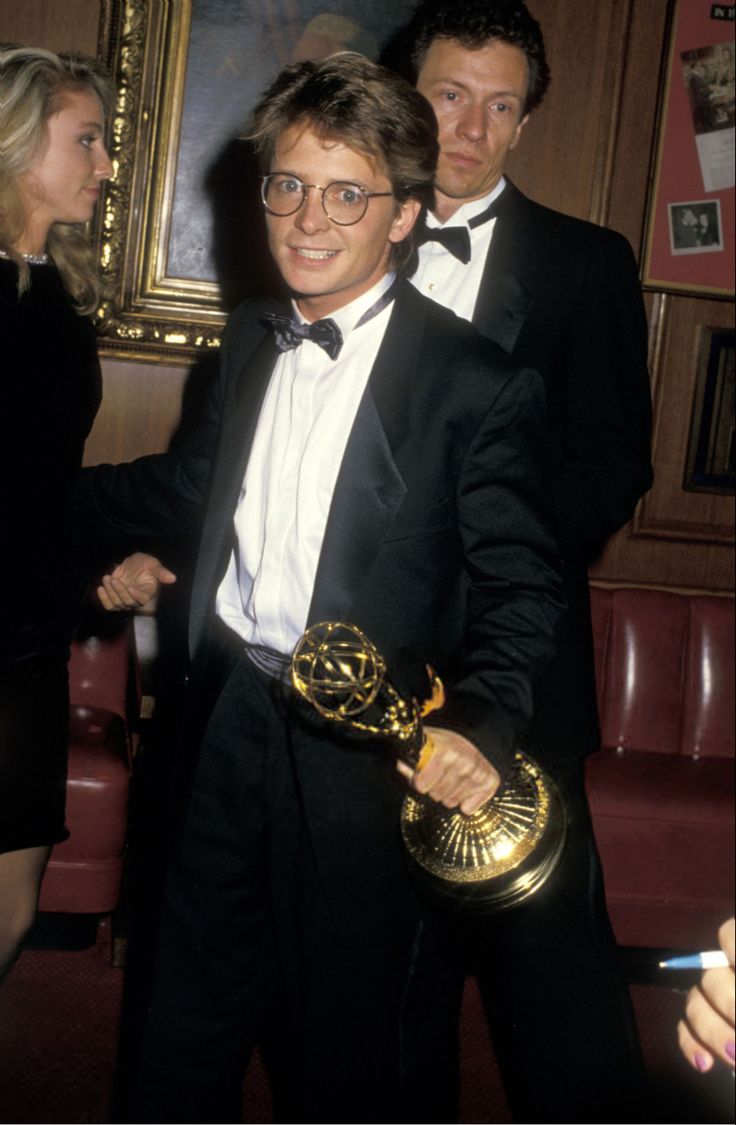 two men in tuxedos are shaking hands with an award for best actor at the 69th annual golden globe awards