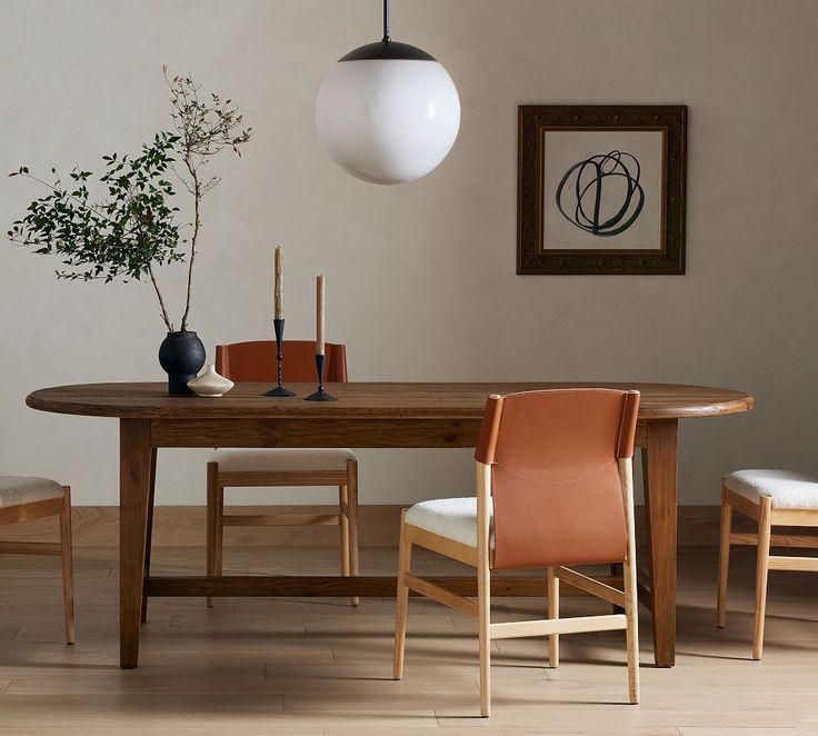 a dining room table with chairs and a vase on the top, in front of a white wall