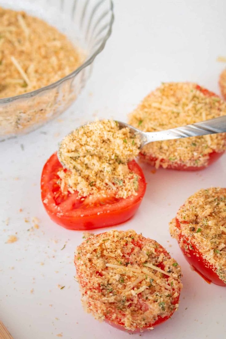 some tomatoes are sitting on a cutting board next to a glass bowl with something in it