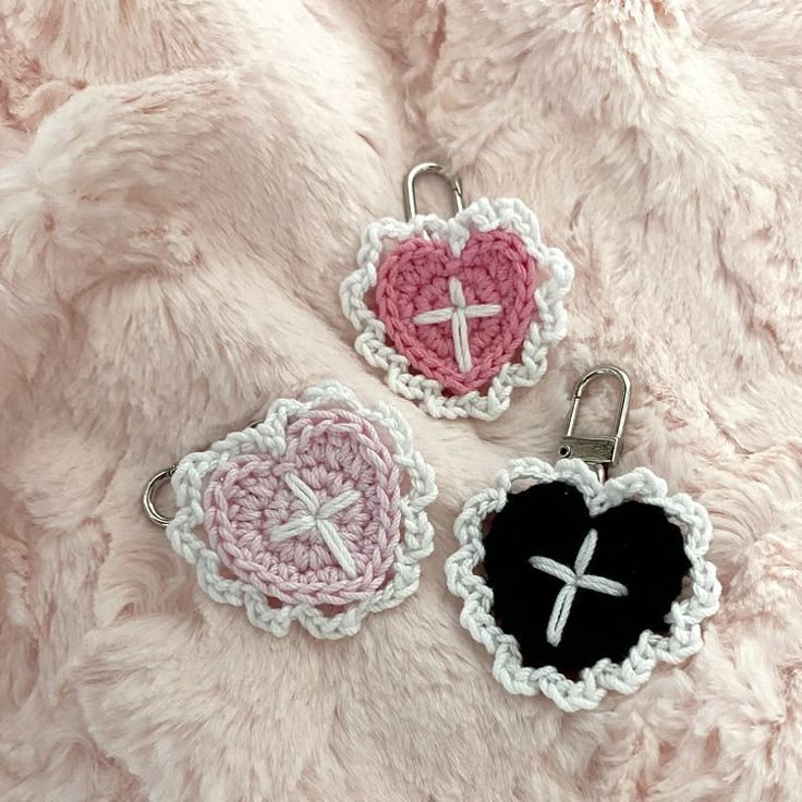 two crocheted heart shaped key chains with a cross in the center and a black heart at the bottom