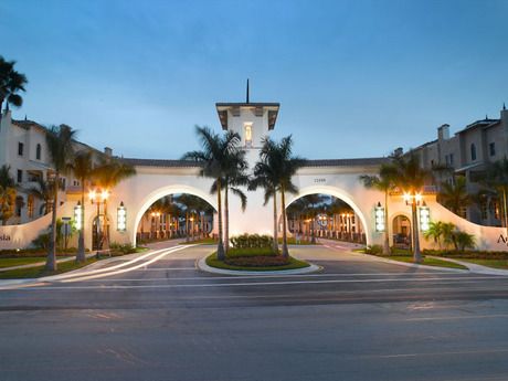 an empty street with palm trees in front of a large white building at night time