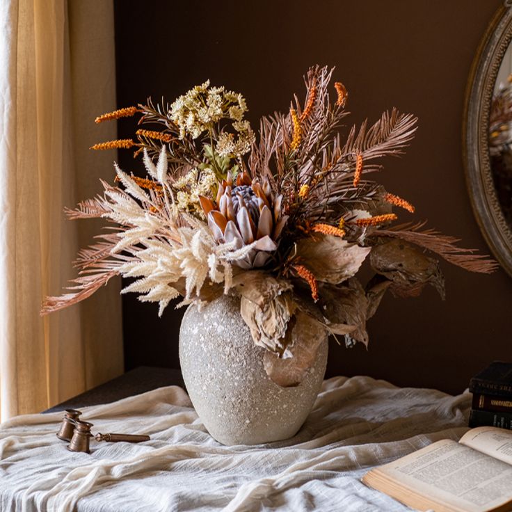 a vase filled with flowers sitting on top of a table next to an open book