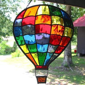 a multicolored hot air balloon hanging from the side of a tree in front of a house