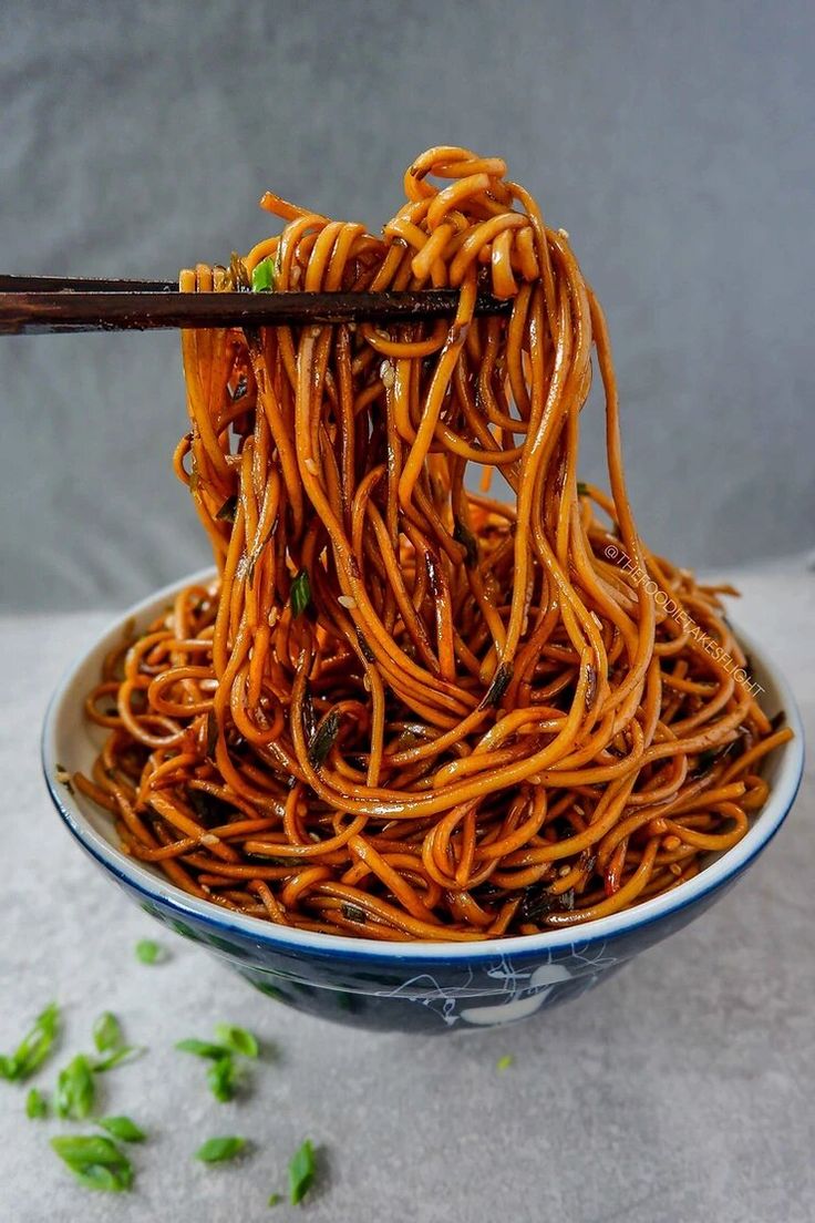 a bowl full of noodles with chopsticks in it