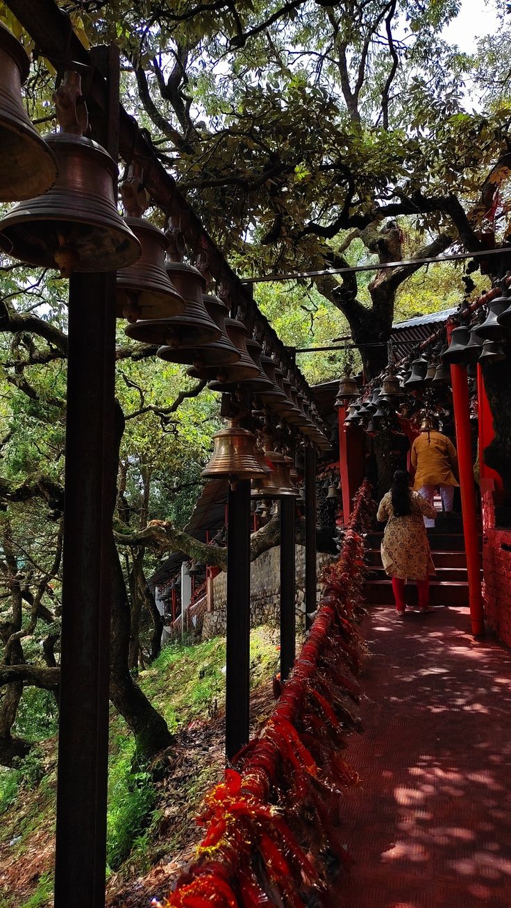 a woman walking down a path next to bells