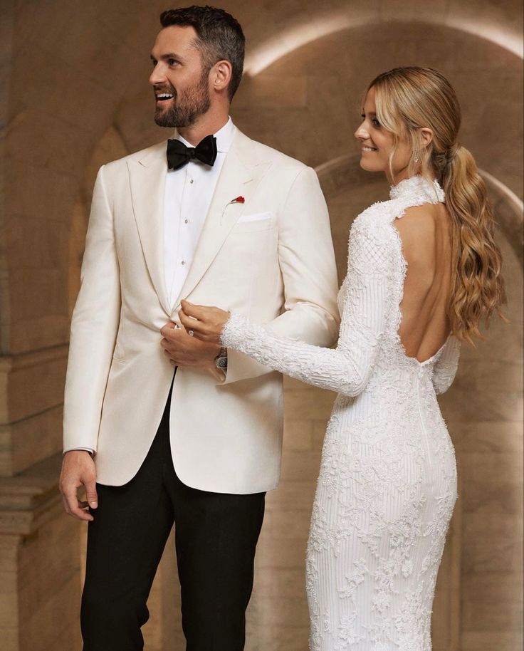 a man in a tuxedo standing next to a woman in a white dress