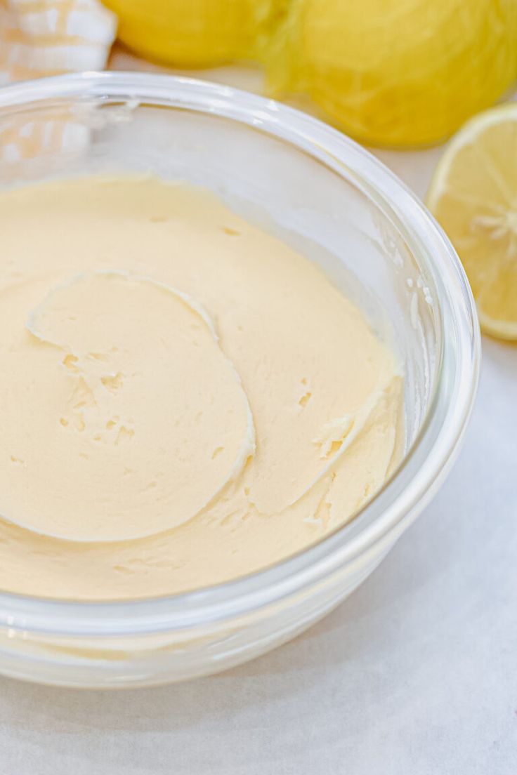 a glass bowl filled with batter next to lemons and other food on a table