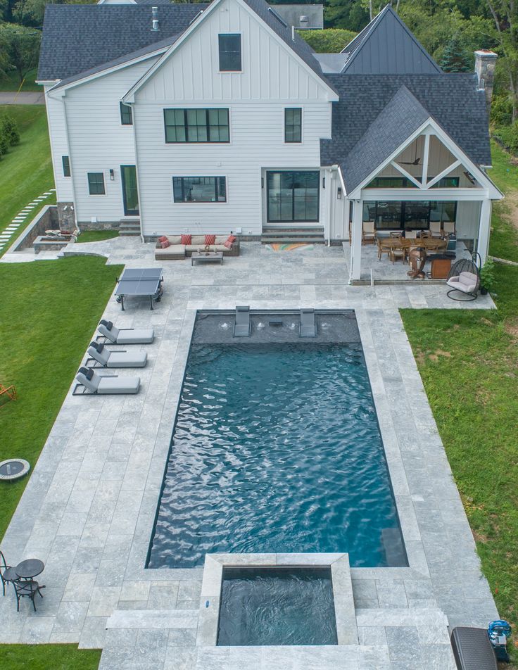 an aerial view of a backyard with a pool and hot tub in the foreground