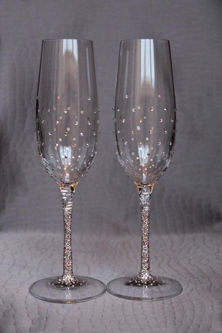 two wine glasses sitting next to each other on top of a white cloth covered table