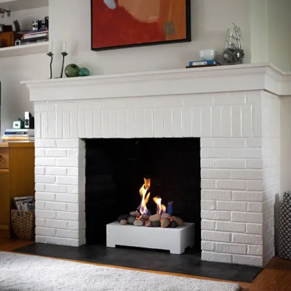 a fire place in the middle of a living room with a painting on the wall