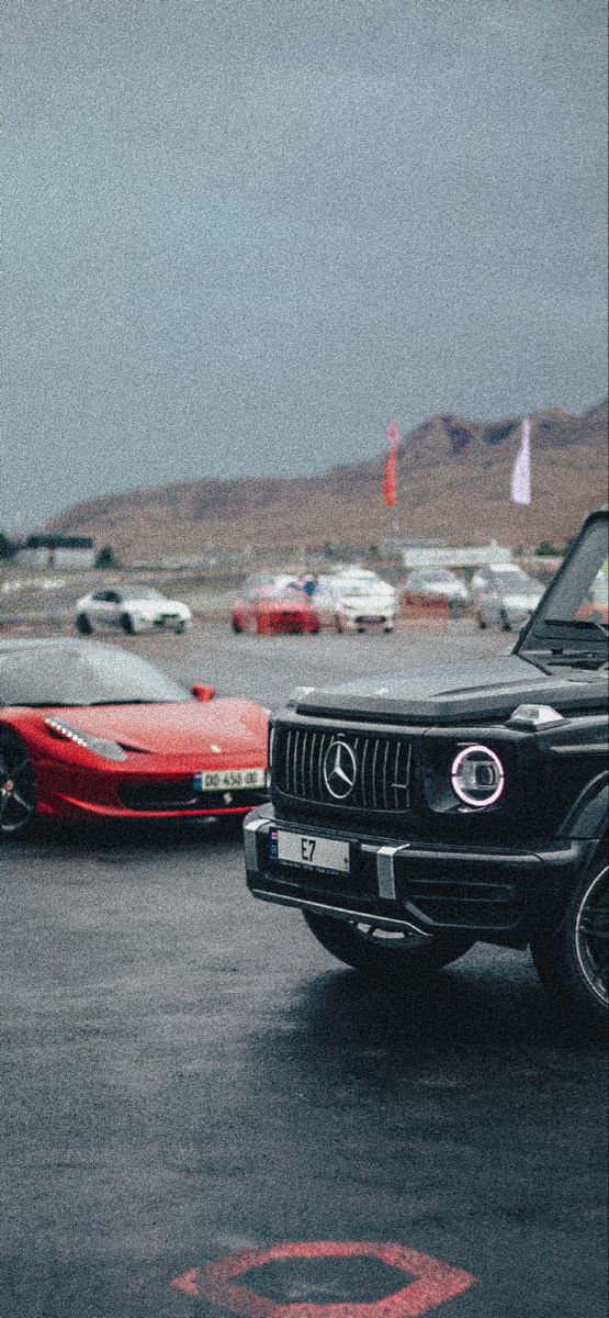 two cars are parked in a parking lot next to each other, one is red and the other is black