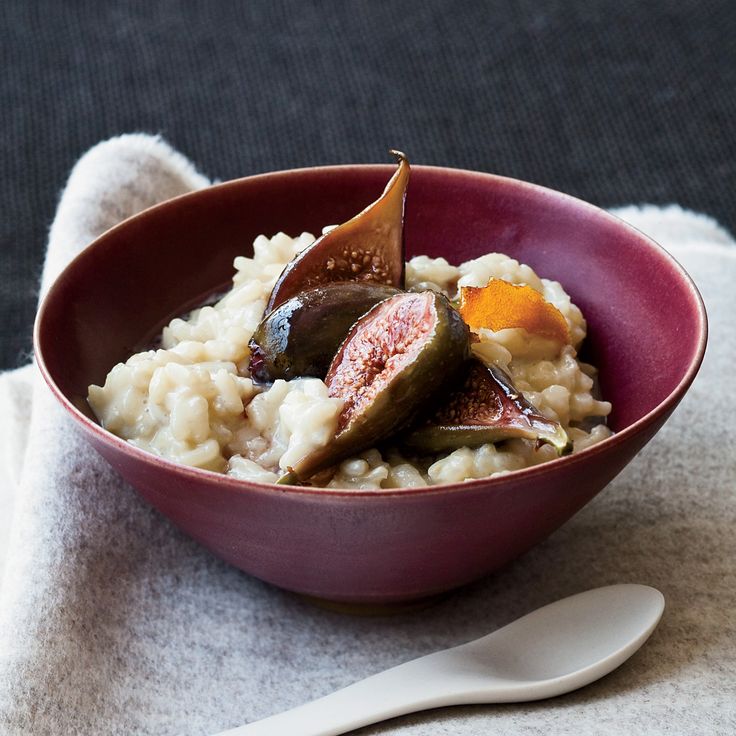 a red bowl filled with rice and meat on top of a white cloth next to a spoon