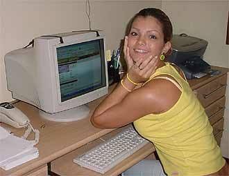 a woman sitting at a desk in front of a computer with a monitor and keyboard