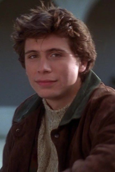 the young man is wearing a brown jacket and looking at the camera with an intense look on his face