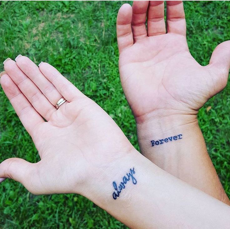 two hands with tattoos that say forever and happy on them, in front of green grass