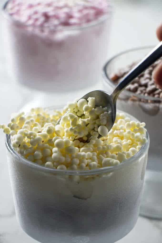 someone scooping popcorn out of a bowl with marshmallows in the background