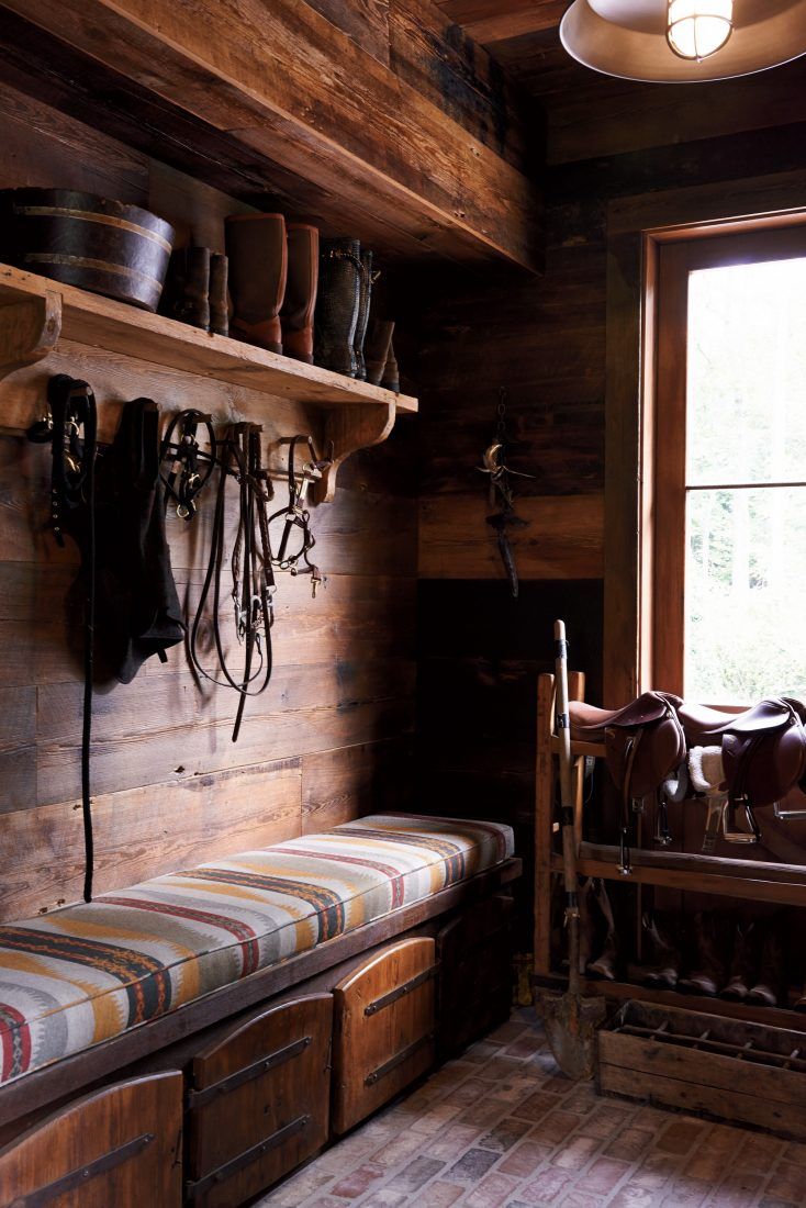 a room with wooden walls and shelves filled with hats, boots and other things on the wall