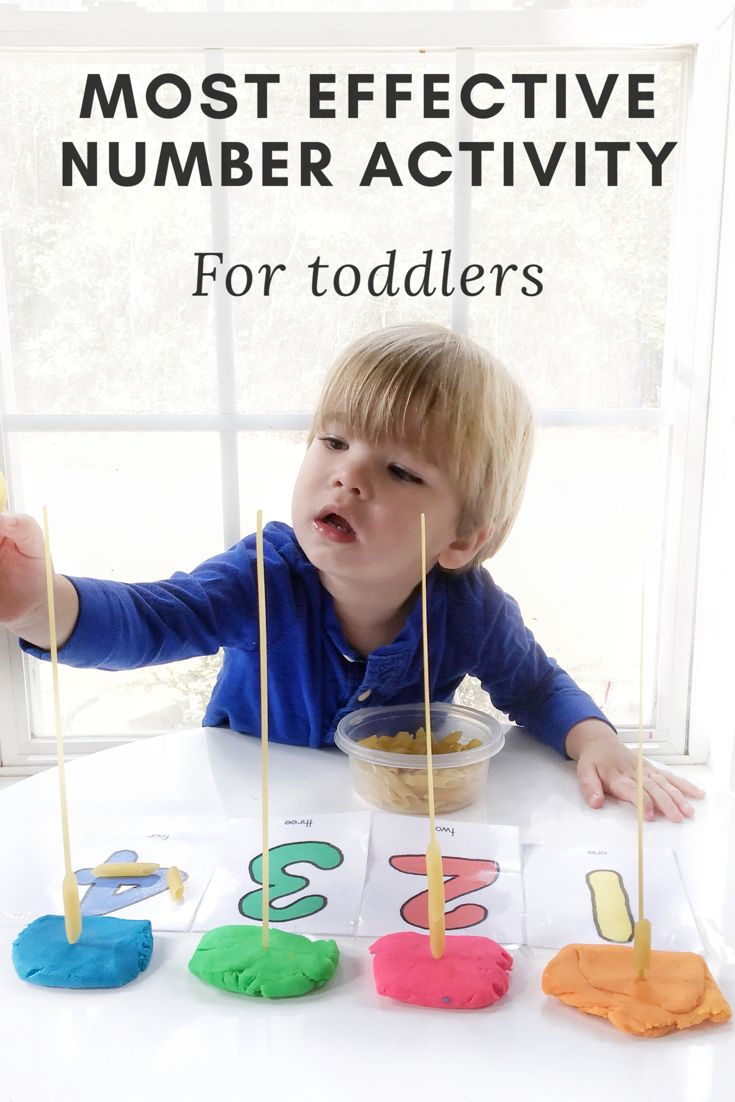 a little boy sitting at a table with some sticks in his hand and numbers on them