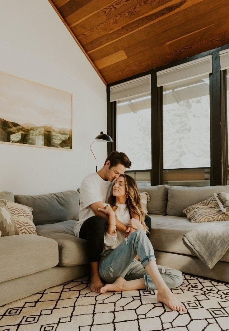 a man and woman sitting on top of a couch in a living room next to each other