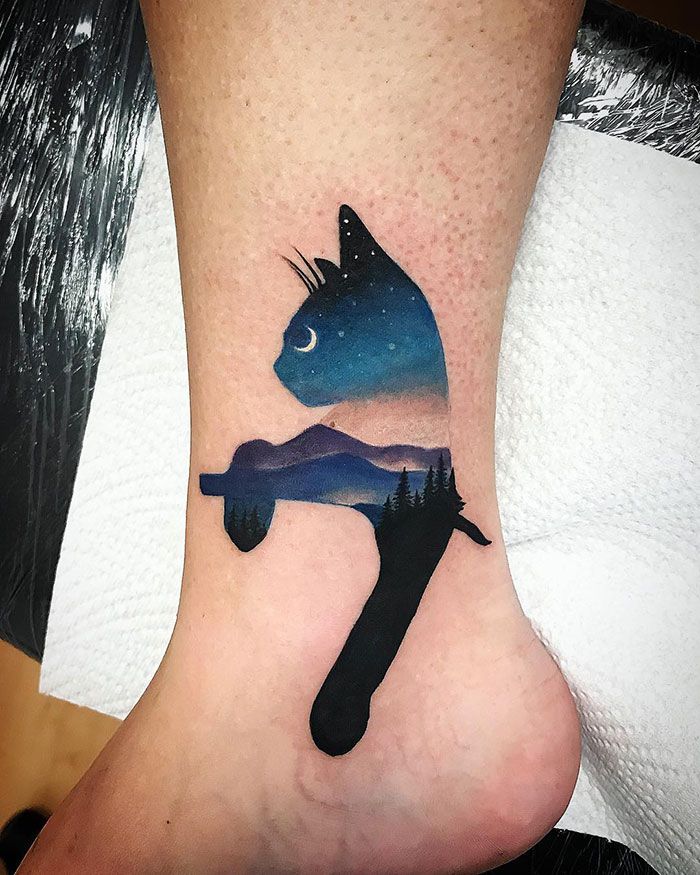 a small tattoo on the ankle of a person's foot with a cat and moon