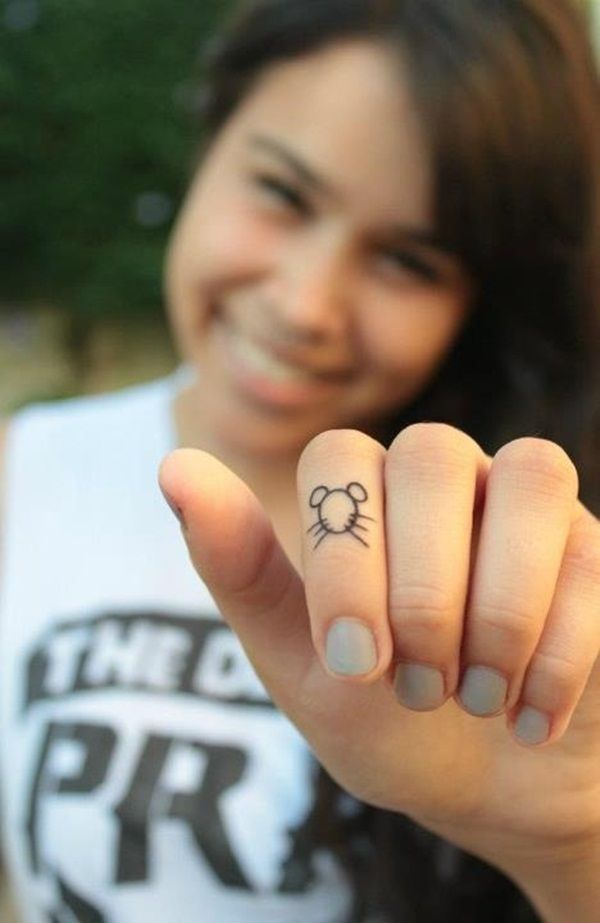 a woman with a cat tattoo on her finger pointing to the camera and smiling at the camera