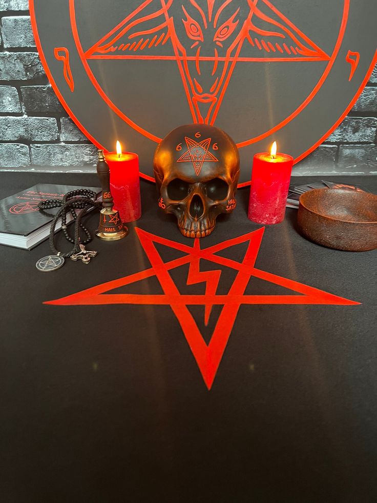 a table topped with candles and a skull next to a pentagramus symbol on top of it