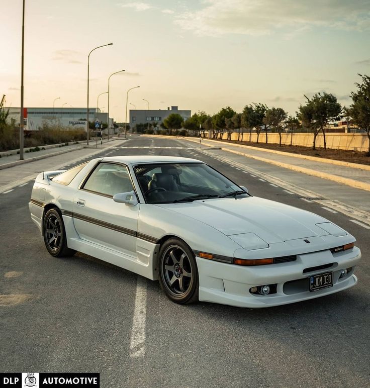 a white sports car parked in the middle of an empty parking lot