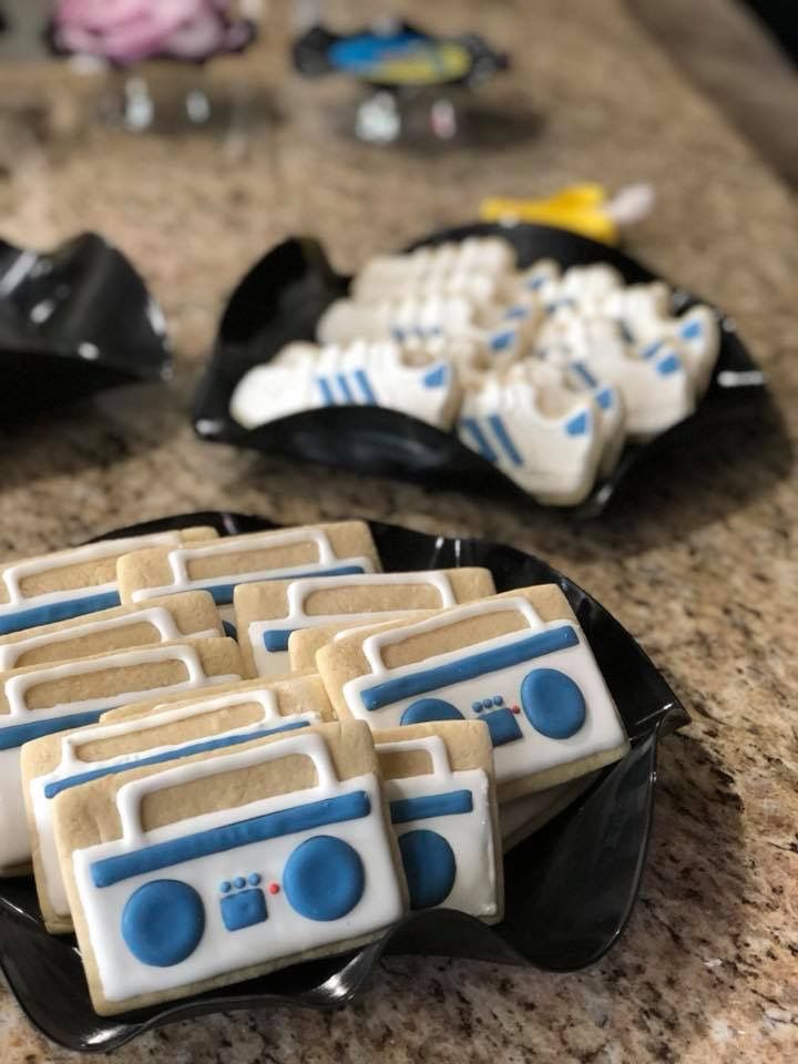 cookies decorated with blue and white icing are on a black plate next to other cookie items