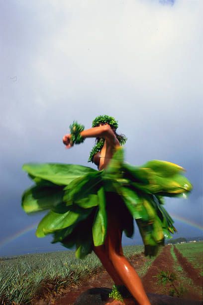 a woman in a green dress is dancing on the grass with a rainbow in the background