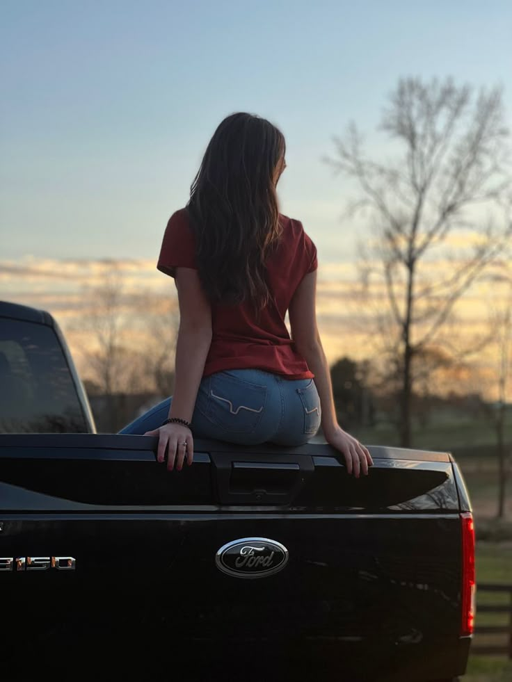 a woman sitting on the back of a pickup truck