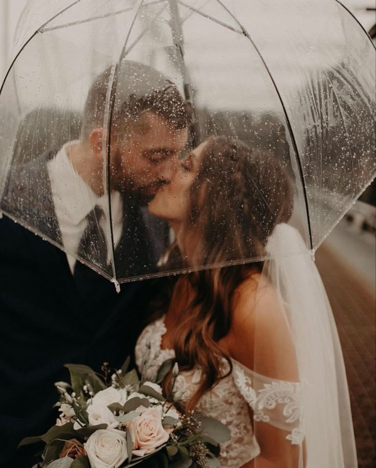 a bride and groom kissing under an umbrella