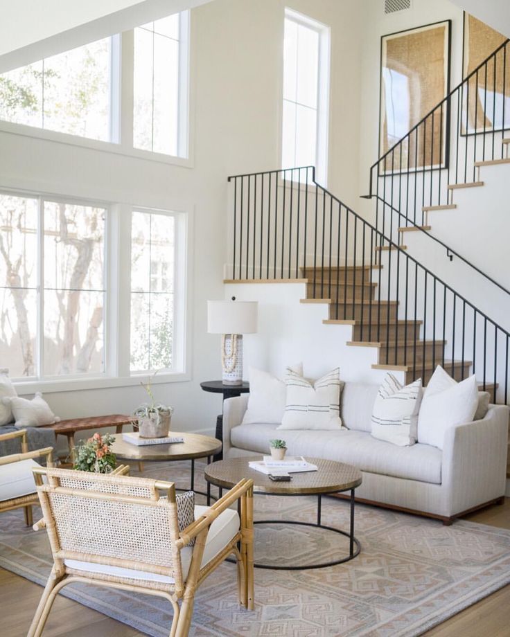 a living room filled with furniture and a stair case in front of a large window