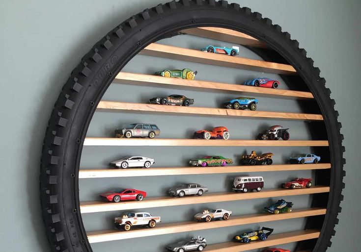 there are many toy cars on the shelves in this wall mounted display case that is made out of tire rims