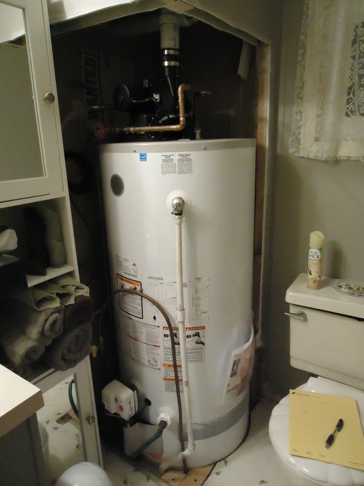 a water heater sitting in the corner of a bathroom