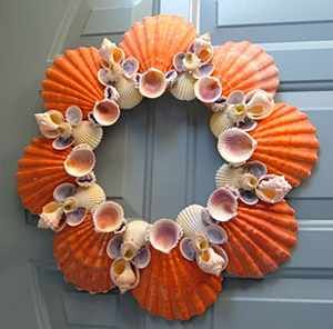 an orange wreath with seashells hanging on the front door