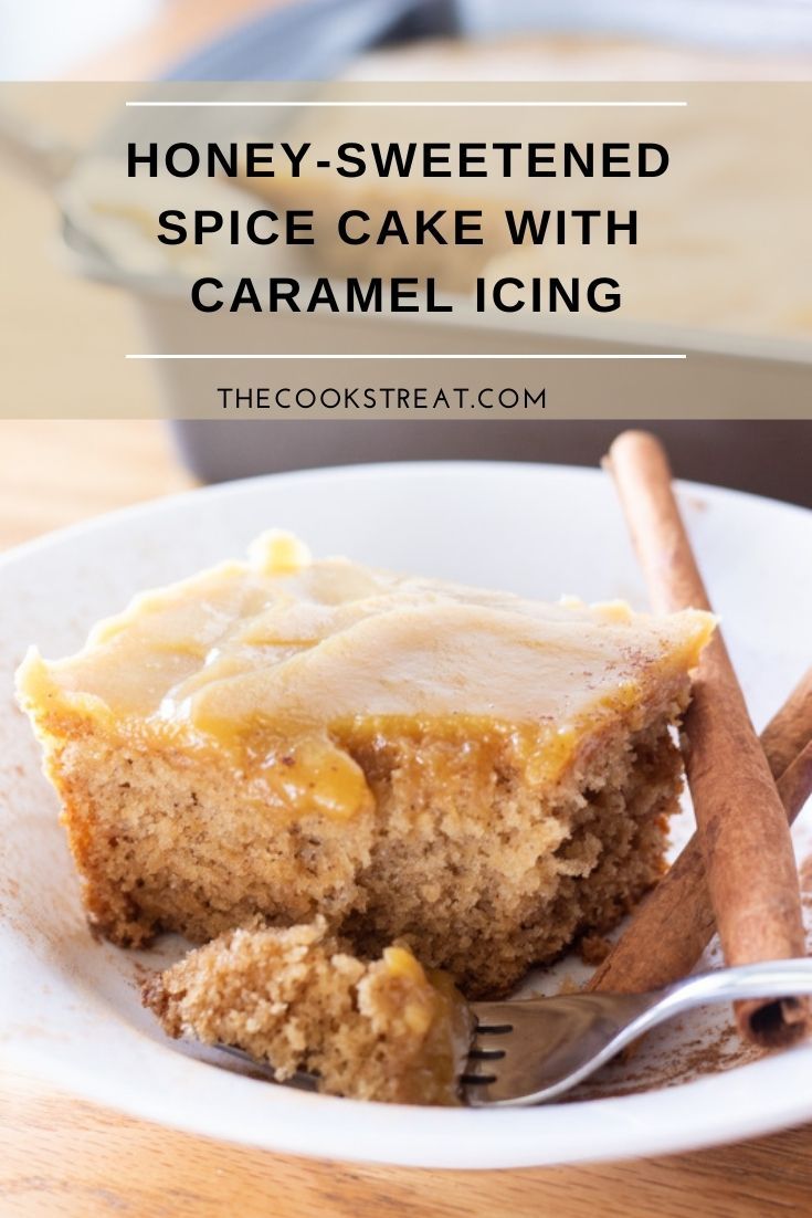 honey - sweetened spice cake with caramel icing on a white plate next to cinnamon sticks