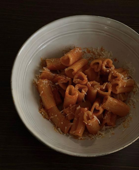 a white bowl filled with pasta on top of a wooden table