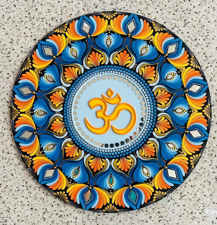 a decorative plate with an om symbol on it's center piece in blue, yellow and orange colors