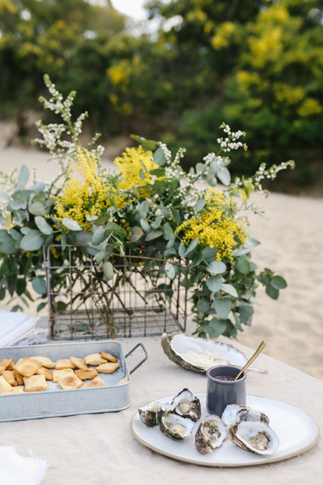 a table topped with oysters next to a potted plant and plate of food