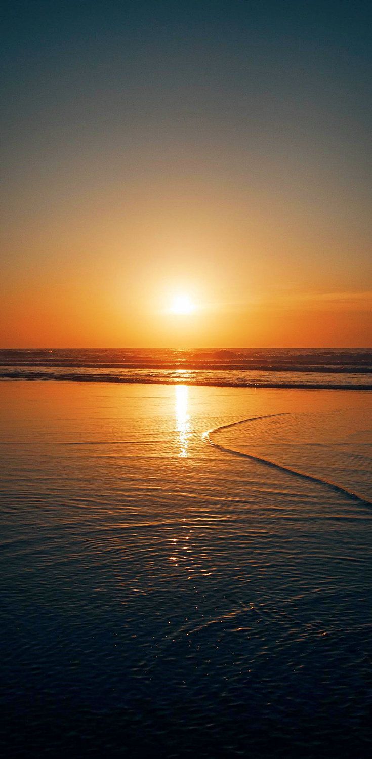 the sun is setting over the water at the beach