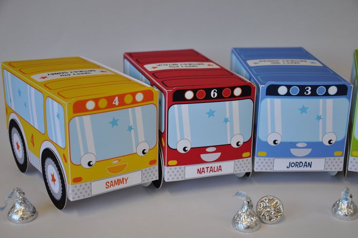 four boxes with candy in them sitting next to each other on a table and one box is shaped like a bus