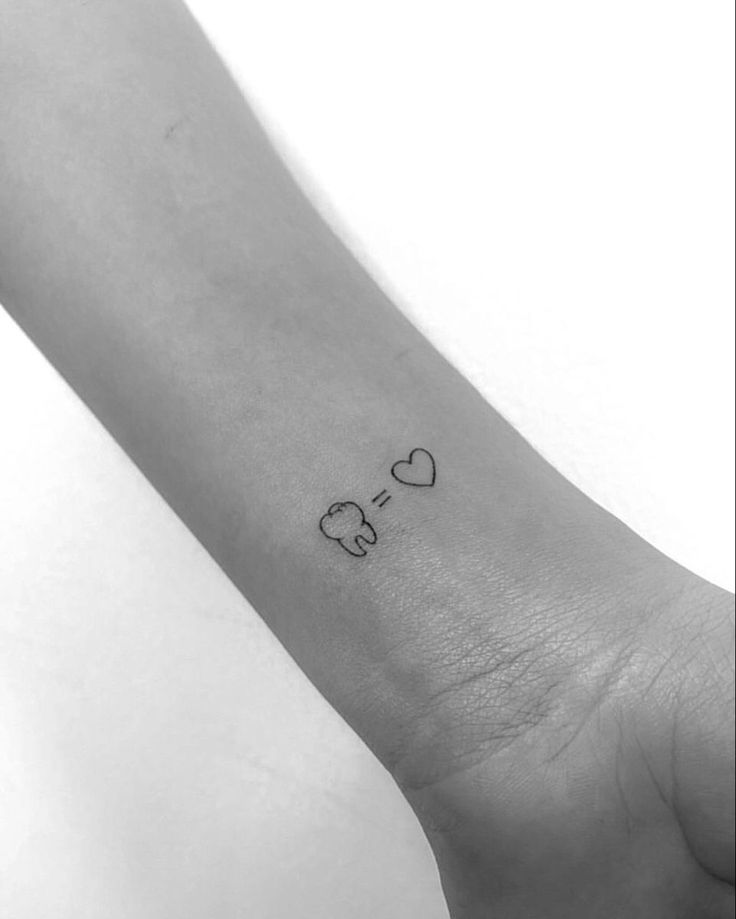 a small elephant tattoo on the left inner arm, with hearts and an elephant in the middle