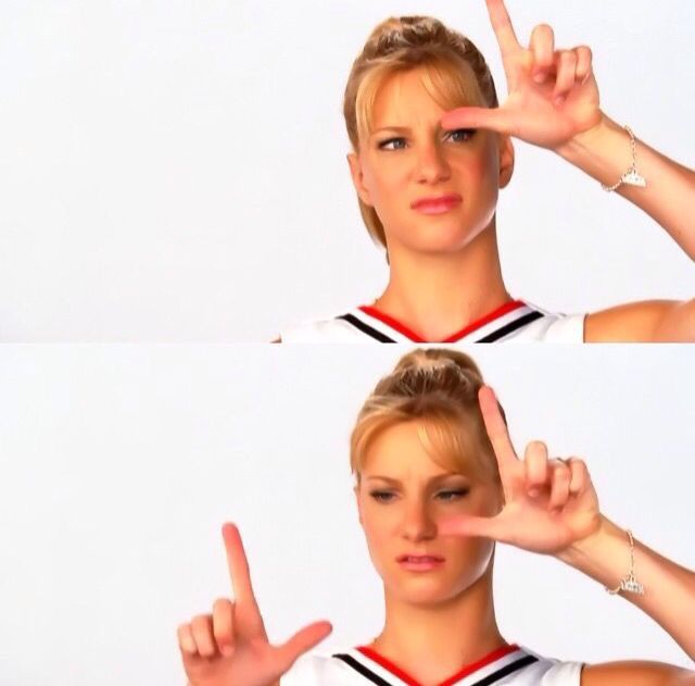 a woman making the peace sign with her hands while wearing a cheerleader shirt and bracelets