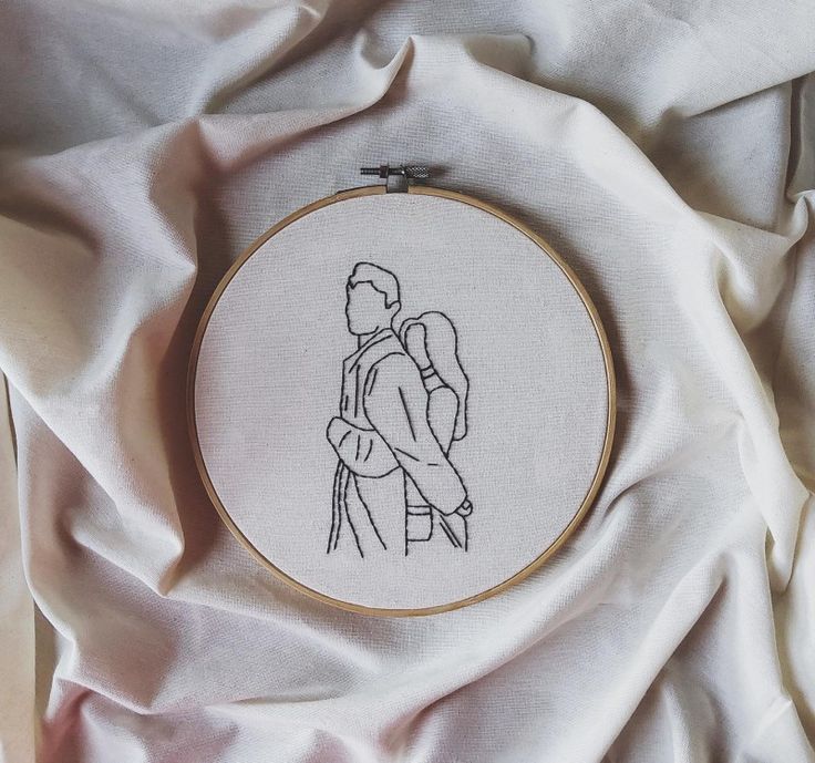 a cross stitched picture of a man and woman hugging each other on a white sheet