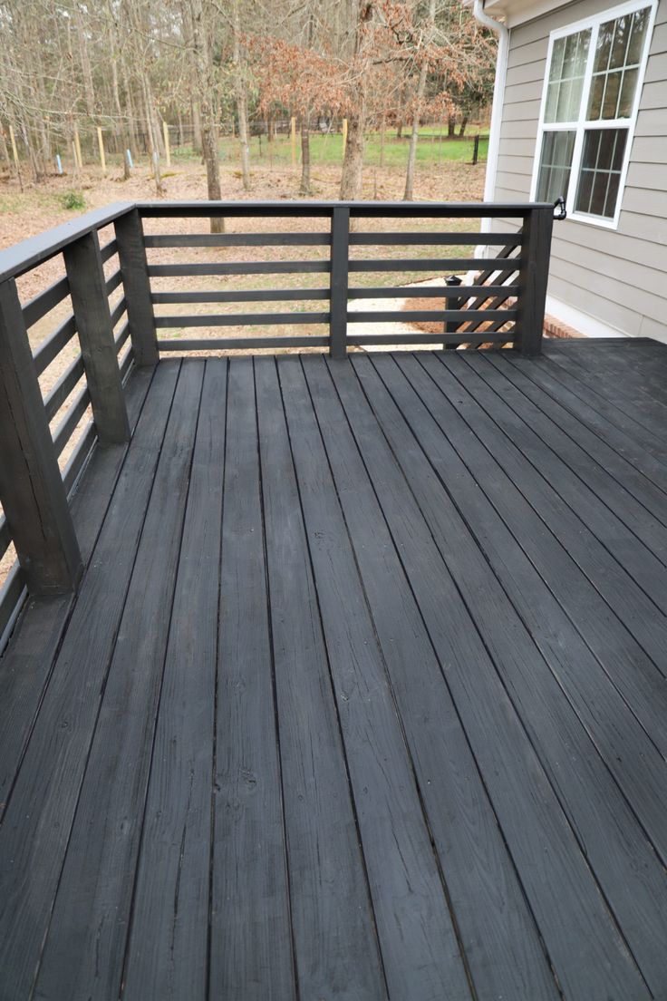 a wooden deck with metal railings in front of a house