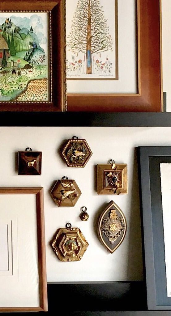 there are many framed pictures on the wall above each other, including one with an ornament